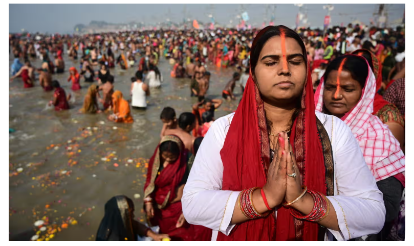 Pilgrims participating in the Kumbh Mela festival, taking ritual baths at the confluence of the Ganges, Yamuna, and mythical Saraswati rivers amidst a large crowd.